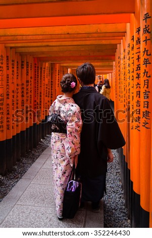 Kyoto, Japan - November 29, 2015: Japanese couple in traditional clothes at the torii gates in  Fushimi Inari Shrine in Kyoto. The shrine is famous for its thousands of vermilion torii gates.