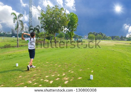 Junior golfer driving golf ball on golf course
