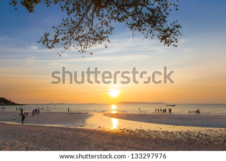 Tropical beach at sunset with group of enjoy people