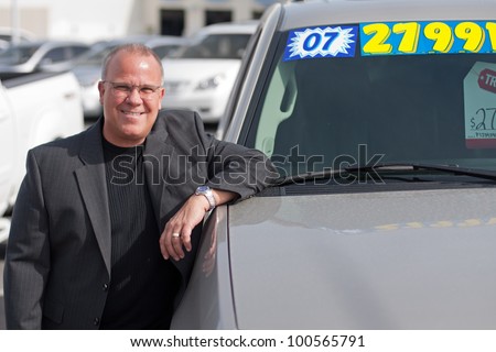 car salesman on lot with price sticker on cae selling