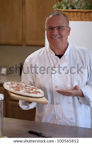 chef with frozen pizza in kitchen presenting
