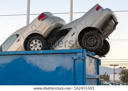 2 junk cars in a dumpster