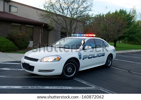 White American Police sedan with red/blue lights on.
