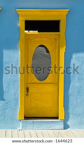 Yellow victorian era door on blue adobe building in the desert southwest.