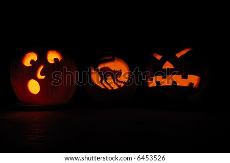 3 scary Jack O\' Lanterns at night with candles inside.