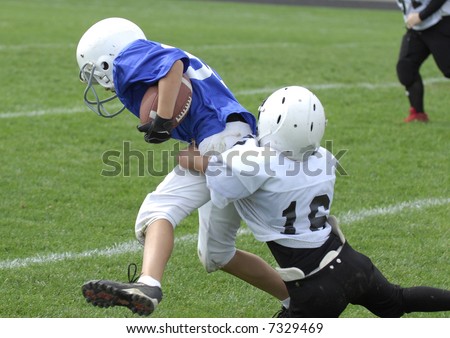 Youth football player tackles another.