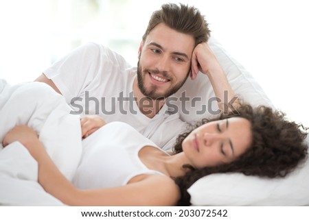 Smiling man and young woman lying on bed