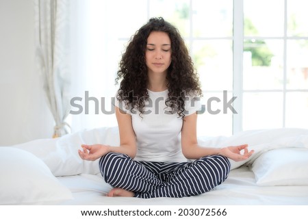 Beautiful woman meditating in bedroom