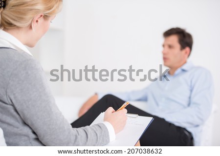 Female psychologist making notes during psychological therapy session
