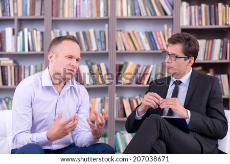Psychologist listening his male patient at office
