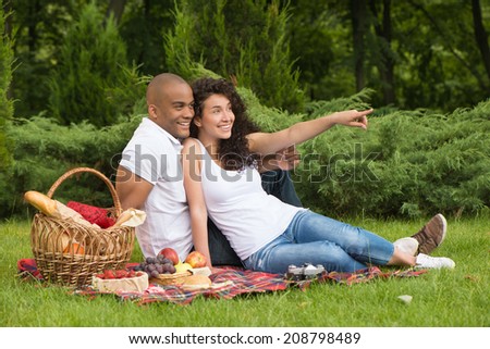 Smiling girl pointing at something while having picnic