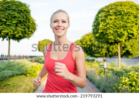 Smiling sport woman running in park