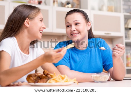 Young woman with well set-up figure eating junk food and young overweight woman on diet