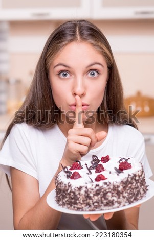 Young woman with well set-up figure wanting to eat secretly big cake