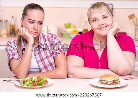 Two contradictions: young woman with well set-up figure and young overweight woman eating healthy and junk food
