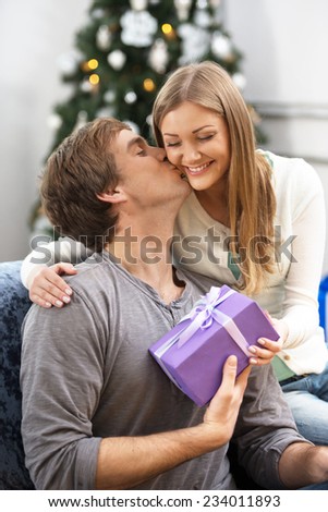 Young beautiful woman giving Christmas present to her boyfriend
