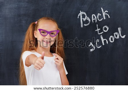 Rad head pupil girl expressing positivity against the blackboard background with \