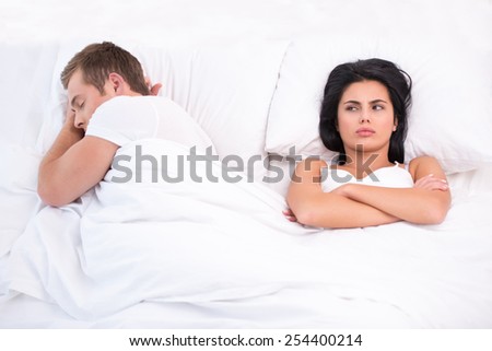 Top view photo of young couple lying in bed under white blanket after a quarrel. Offended and sleepless woman