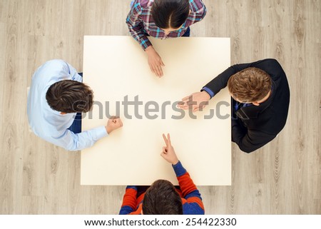 Top view of table with group of creative people playing rock paper scissors game