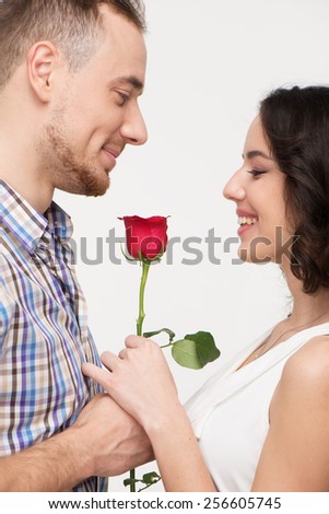 Man giving red rose to his beloved. Woman smiling. She is pleased to receive a gift. Isolated on white background