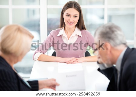 Young woman having an interview or business meeting with employers. Employers examining her CV. Office interior with big window