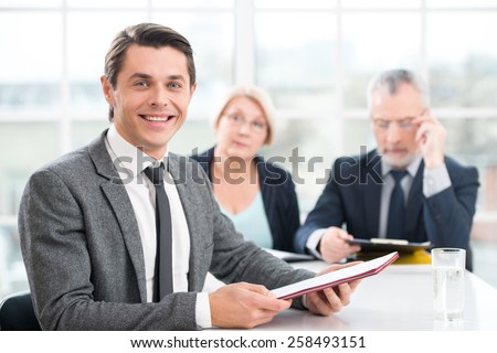 Happy smiling man having an interview or business meeting with employers. Office interior with big window