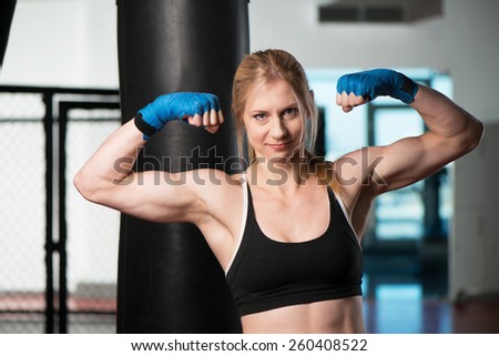 Sporty stern woman holding up boxing gloves at the gym