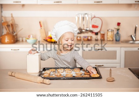 Little cute girl with chef hat preparing cookies. Kitchen interior. Concept for young kitchen hands