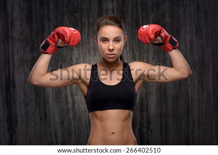 Young mixed race sporty woman wearing black tracksuit for training with red boxing gloves. She looking at camera powerfully. Fitness concept