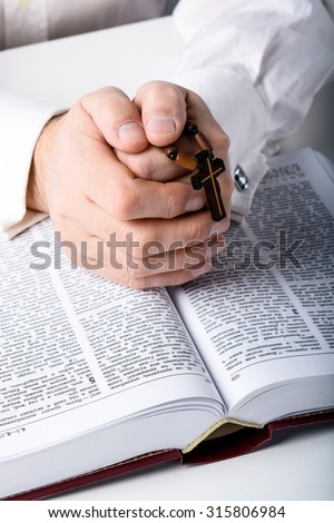 Photo of old man hands with rosary and open Bible
