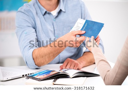 Close up photo of male travel agent and young woman. Young man giving tickets and passport with visa to female tourist