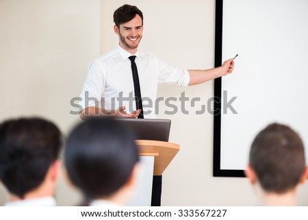 Photo of handsome young businessman making presentation with whiteboard on seminar or meeting to business people