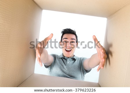 Man smiling, unpacking and opening carton box, and looking inside
