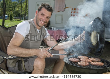 Handsome man at a barbecue grill with smoke