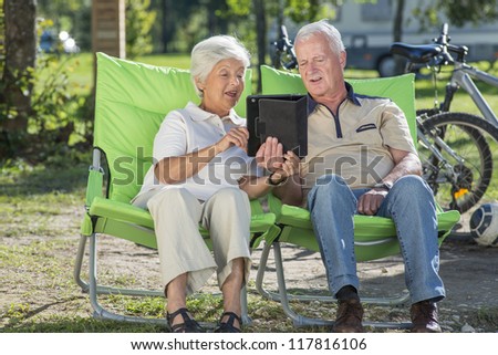 Senior couple relaxing in camp, having fun using their tablet PC