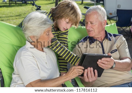 Grandson teaching his grandparents using digital tablet outdoors