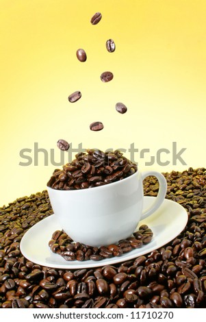 Coffee beans falling over a coffee cup