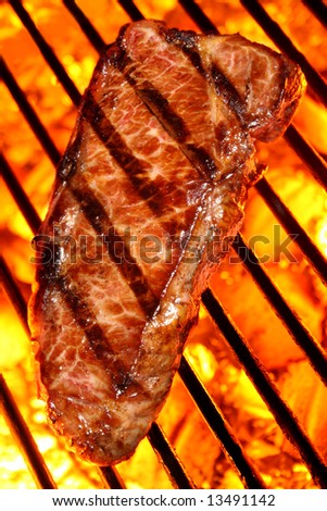 Grilled beef steak on a fire hot barbecue grill.