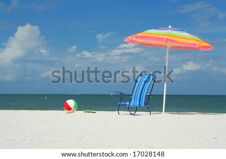 Beach chair, umbrella, flip-flops and ball on a sunny day at the beach