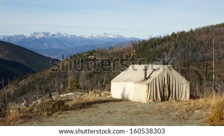 Deer Hunting Camp in the Mountains with an old canvas wall tent and a wood stove chimney pipe. National Forest wilderness camping in fall / autumn Washington Oregon Montana Idaho Wyoming Colorado