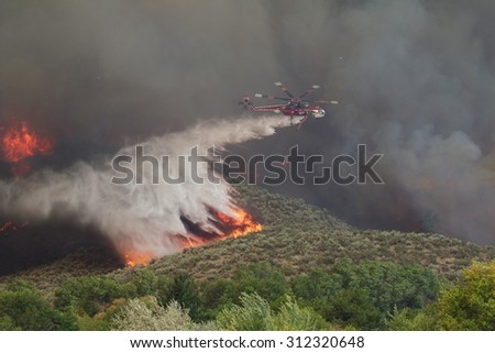 Riverside, WA, USA August 18, 2015: A helicopter dumps hundreds of gallons of water to extinguish flames on the Okanogan Complex Wild Fire, Washington state\'s largest, most destructive fire ever