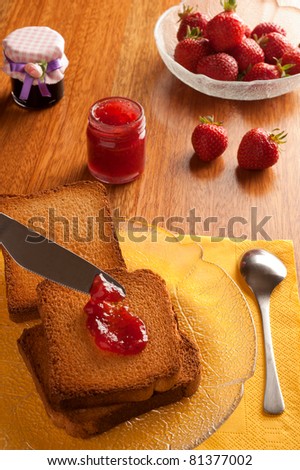 breakfast on a wooden table with strawberry marmalade and toasted bread