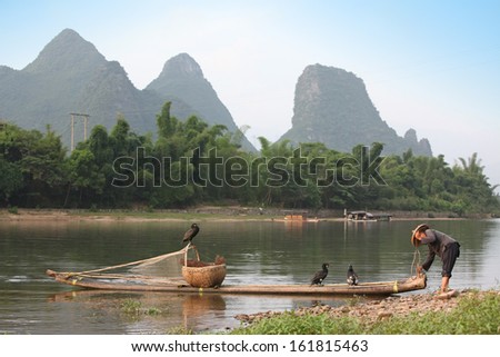Chinese man preparing fo fishing with cormorants birds, traditional fishing use trained cormorants to fish in China