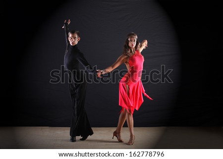 Latino dancers in ballroom against black background