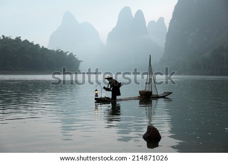 Chinese man fishing with cormorants birds, traditional fishing use trained cormorants to fish,China