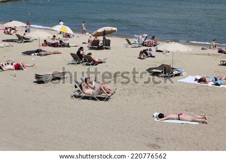 BARCELONA - JUNE 11: At the beach with tourists and locals in summer on June 11, 2013 in Barcelona, Spain. Barcelona is a famous destination for hundred of thousands of tourists a year