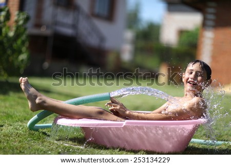 The boy in bath in hot summer day outdoors
