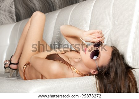 Seductive brunette girl in sun glasses and golden bikini