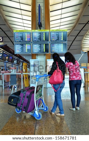 SINGAPORE -OCT 15: Unknown passagers check information board at Changi airport on October 15, 2013 in Singapore. Changi Airport serves more than 100 airlines connecting Singapore to over 220 cities