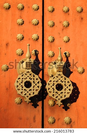 Typical old rustic studded wooden door with Islamic patterns on brass door-knock, Morocco.